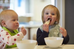 Two young girls eating breakfast in a childcare centre