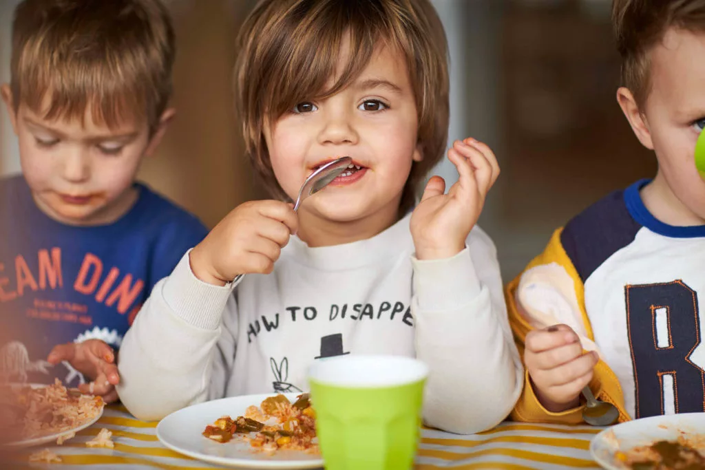 Three boys eating food together