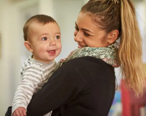 Baby being held by educator and smiling smiles