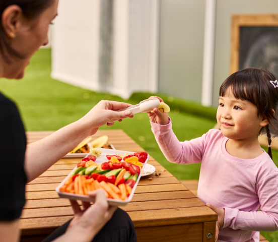 Child serving fruit with tongs