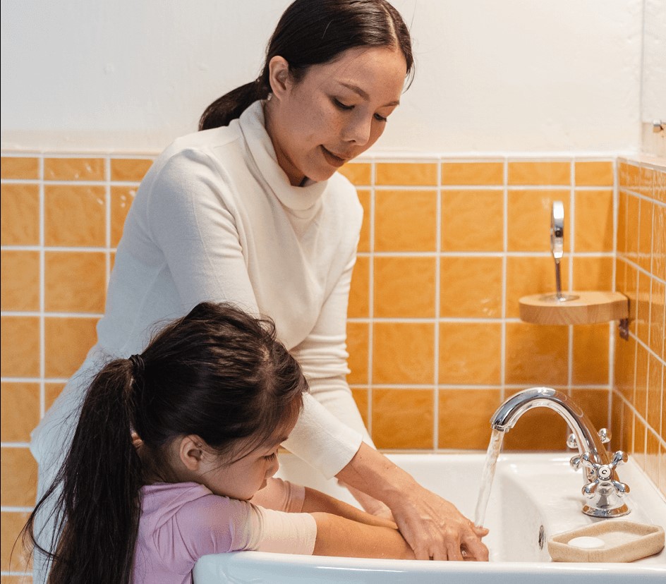 Woman helps child wash hands