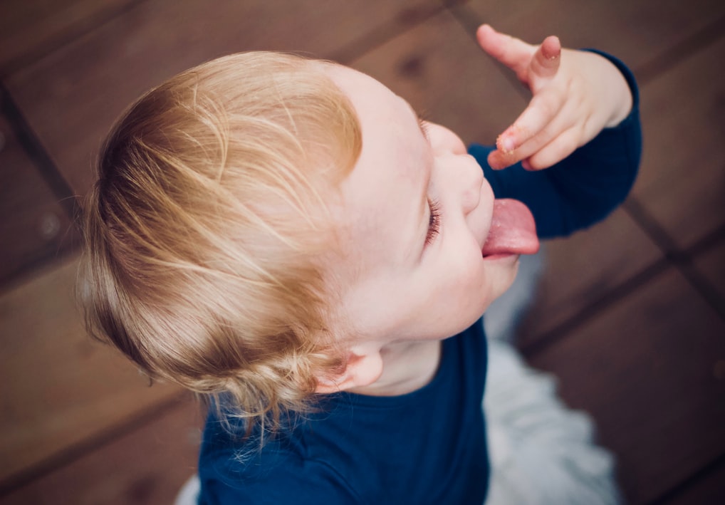 Small child licking their fingers after eating